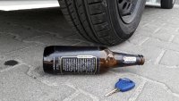 butelka alkoholu leżąca przy samochodzie