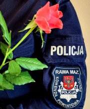 Rękaw munduru z napisem policja Komenda powiatowa Policji w Rawie Mazowieckiej oraz róża koloru różowego.