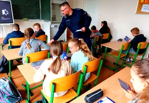 Policjant rozdaje dzieciom plany lekcji w klasie.
