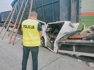 Nieumundurowany policjant wykonujący oględziny samochodów biorących udział w wypadku.