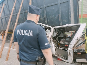 Umundurowany policjant obok rozbitego samochodu.