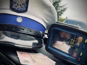 Czapka policjanta, prawo jazdy i urządzenie do mierzenia prędkości na podszybiu radiowozu.