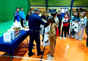 policjant i policjantka wręczają dzieciom nagrody.