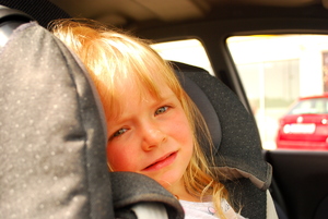 Dziewczynka siedząca w foteliku samochodowym.