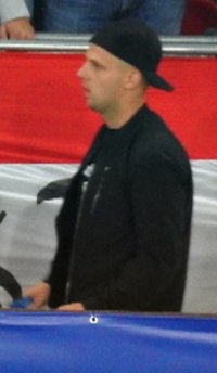 zdjęcie kibica w ciemnej bluzie i ciemnej czapce z daszkiem założonej do tyłu