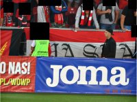 zdjęcie kibica jw oraz baner reklamowy na stadionie  z napisem JOMA