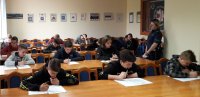 uczestnicy turnieju podczas pisania testu wiedzy i policjantka