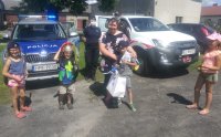 Policjantka, strażak, Jacek z rodzeństwem i mamą na tle samochodów.