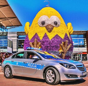 Radiowóz policyjny oznakowany w tle żółty kurczak wykluwający się z jajka.