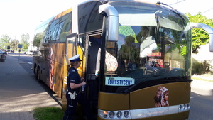 autobus stojący na parkingu i policjantka dokonująca kontroli drogowej