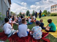 Dzieci siedzące obok budynku  i policjanci.