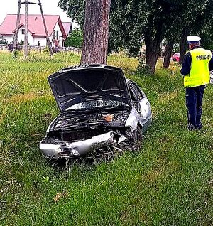 Samochód z otwartą pokrywą silnika i stojący obok policjant w mundurze.