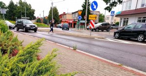 Kobieta przechodząca przez przejście i samochody na drodze.