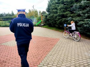 Policjant ruchu drogowego oraz młodzież podczas egzaminu praktycznego.