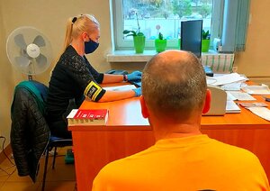 Policjantka siedząca bokiem przy komputerze oraz siedzący tyłem mężczyzna.