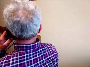 Mężczyzna siedzący z telefonem w ręce.