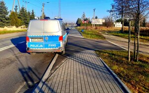 Radiowóz stojący na drodze przed przejazdem kolejowym.