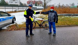 Policjantka w mundurze, radiowóz, rower i mężczyzna.