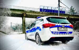 radiowóz, śnieg i przejazd kolejowy