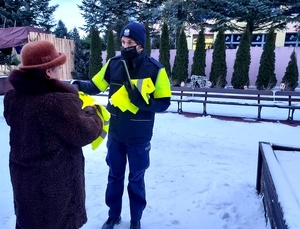Policjantka wręcza seniorce elementy odblaskowe.