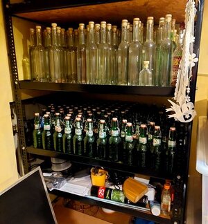 Metalowy regał na którym poustawiane są butelki.