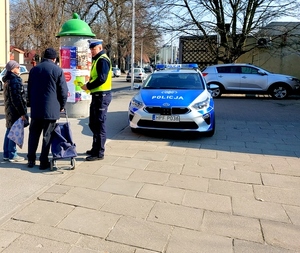 Policjant wręcza odblaski mężczyźnie i kobiecie.