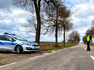 Radiowóz policyjny , auto na drodze i policjant w mundurze.