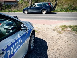 Radiowóz policyjny i samochód na poboczu.
