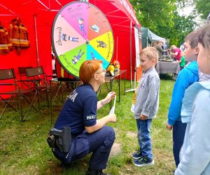 Policjantka w mundurze kucająca przed dzieckiem.