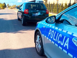 Radiowóz policyjny oraz samochód stojący na drodze.
