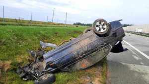 Auto leżące na dachu, całe z ziemi obok droga i samochody.