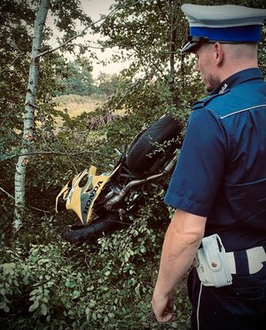 Umundurowany policjant ruchu drogowego na miejscu wypadku z udziałem motocyklisty.