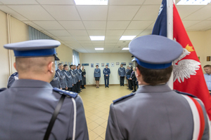 Policjanci w mundurach oraz sztandar.