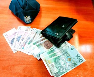 Na stole portfel, czapka policyjna i pieniądze.