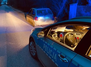 radiowóz policyjny z włączonymi światłami a przed nim auto.