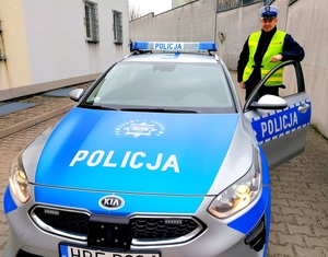 policjant stojący przy radiowozie.