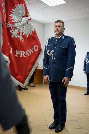 komendant stojący przed sztandarem.