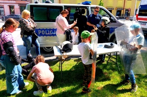 dzieci i dorośli przy radiowozie i policjant.