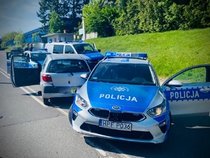 trzy radiowozy policyjne o jeden samochód osobowy na poboczu drogi.