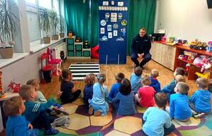 policjant siedzący na małym krzesełku a przed nim dzieci.