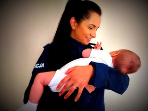 policjantka w mundurze trzyma na rękach malutkie dzieciątko.