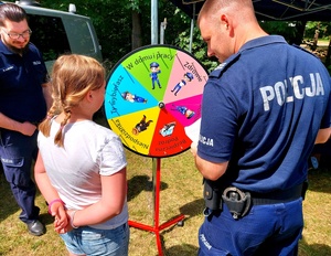 policjanci i dziewczynka stojąca przed kołem fortuny.