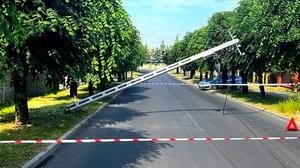 radiowóz stojący na poboczu pomiędzy drzewami nad droga wiszące linie energetyczne i złamany słup.