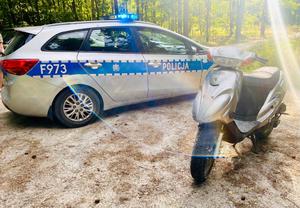Skuter stojący obok oznakowanego radiowozu.