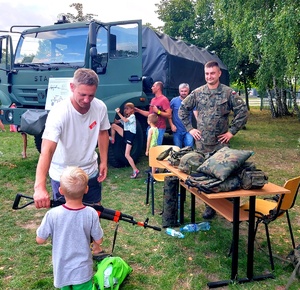 Mężczyzna i dziecko przy samochodzie wojskowym.