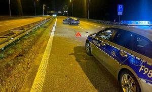 Radiowóz stojący na drodze, w oddali rozbite auto.