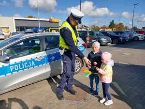 Policjant daje odblaski dwójce małych dzieci.