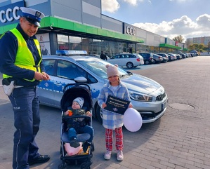 Policjant z małymi dziećmi, daje im odblaski.