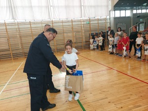 Policjant wręcza nagrody dzieciom.