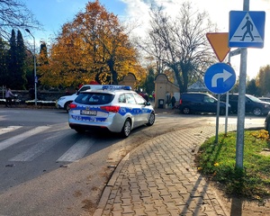 Radiowóz przejeżdżający na skrzyżowaniu. Znaki drogowe.